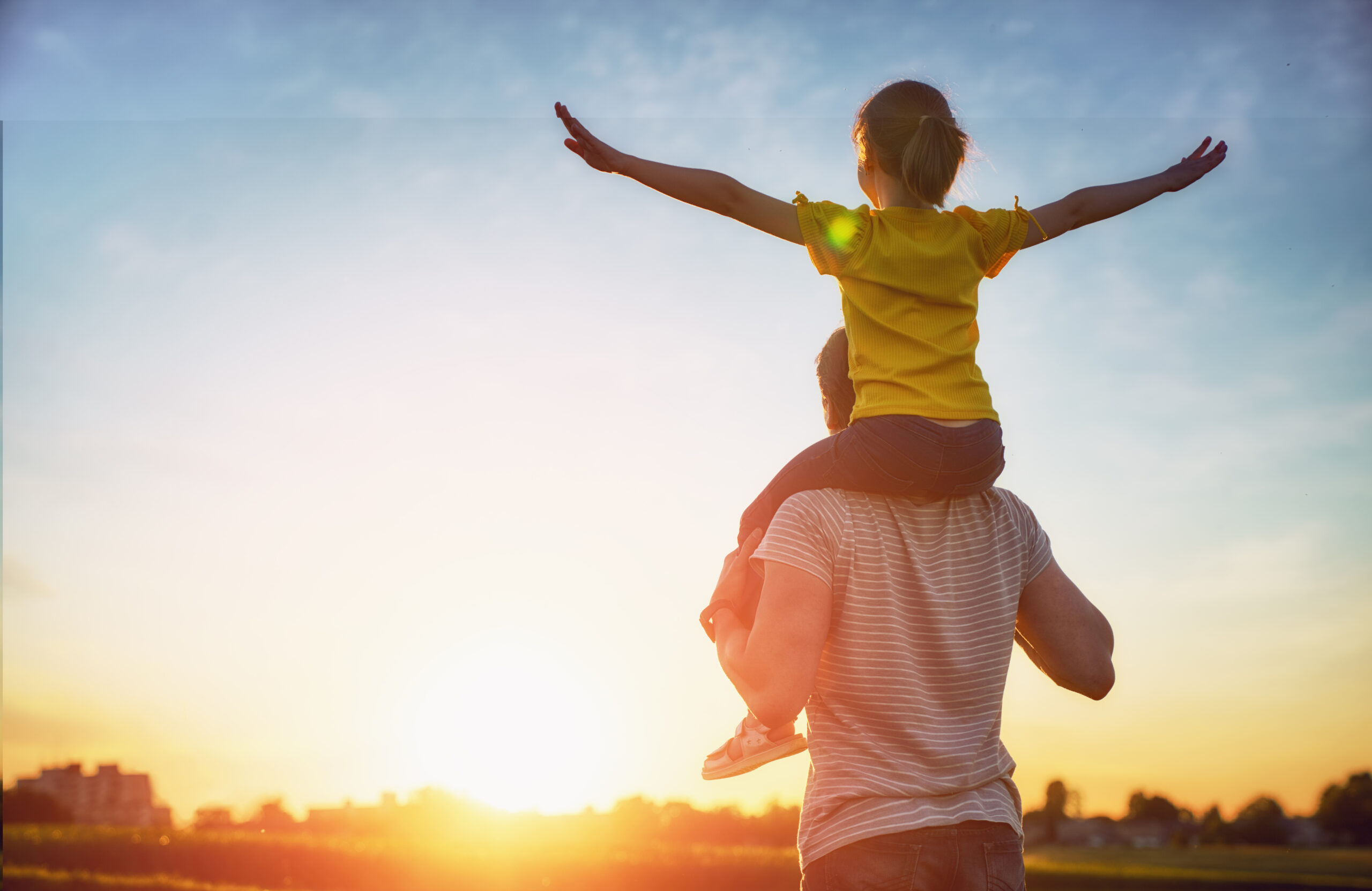 Child sitting on parents shoulders.